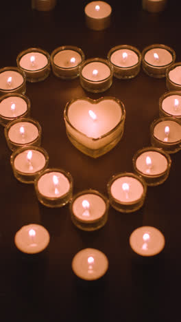 Vertical-Video-Of-Romantic-White-Candles-In-the-Shape-Of-A-Heart-On-Black-Background-1